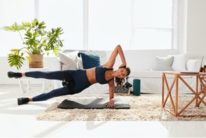 Smiling woman in well-lit room doing a horizonal Pvolve workout