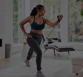 a woman in a sports garment and leggings holding a resistance band