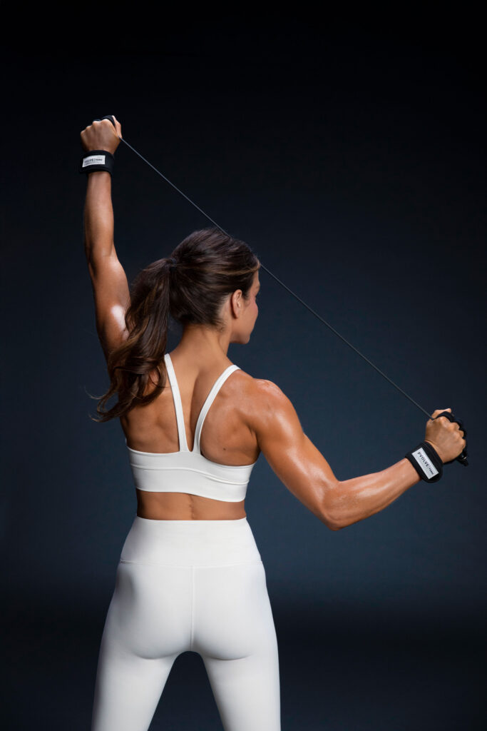 Woman performing a Pvolve strength workout using resistance equipment in a studio setting, focusing on functional movement and core engagement.