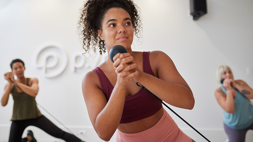 Woman in pink athletic wear focuses on exercise using p.3 trainer