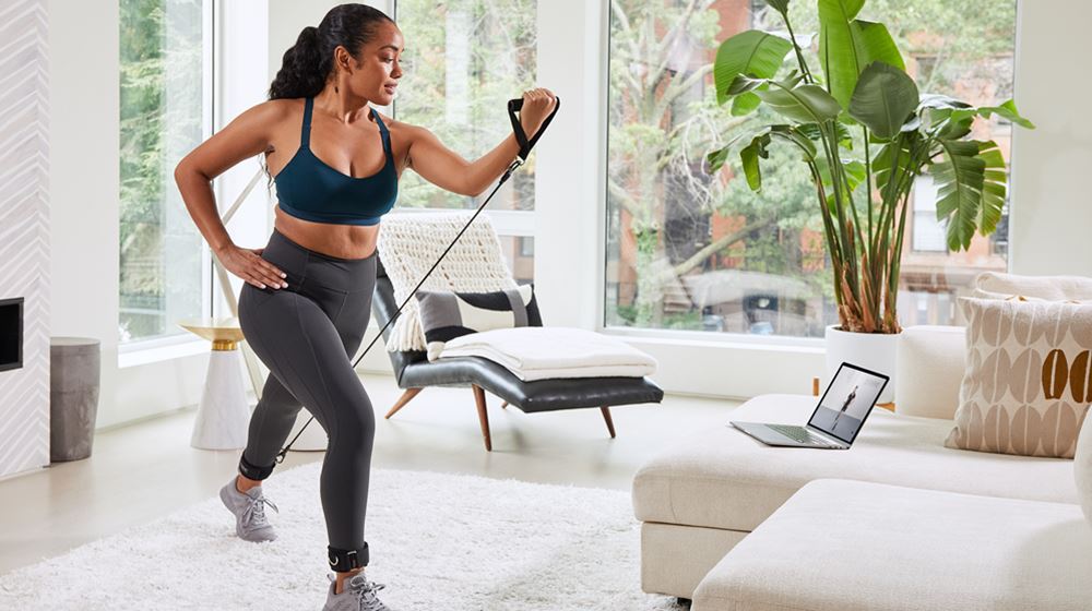 Woman in her home follows along with P.volve class on her computer