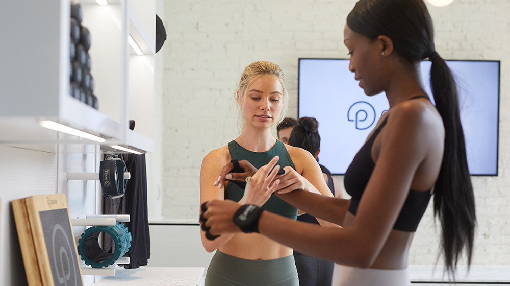 A female P.volve trainer helps a member prepare for a workout.