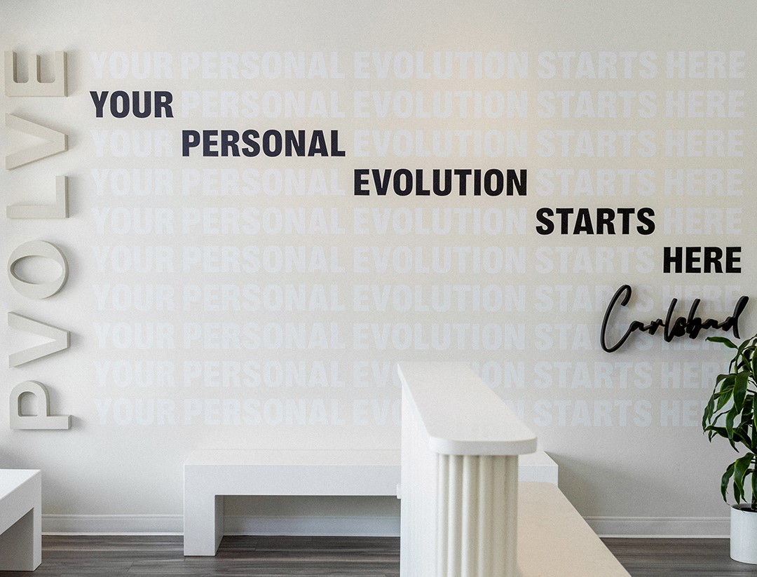 Pvolve front desk with wall art reading "Your Personal Evolution Starts Here"